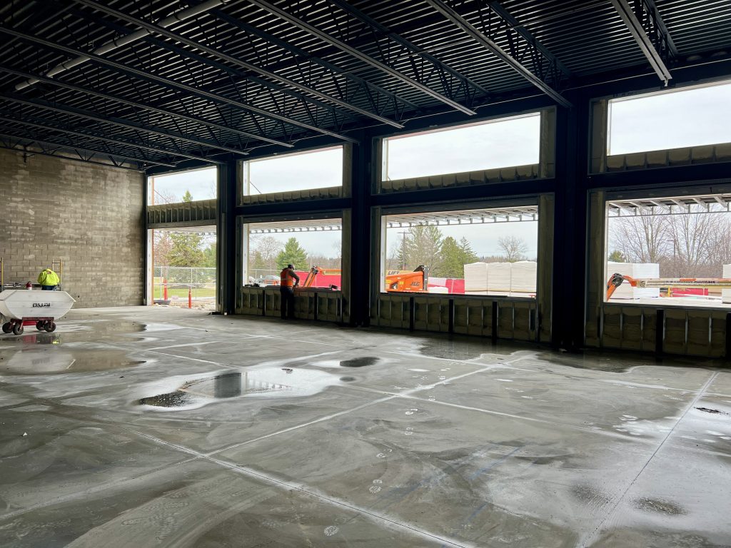 inside incomplete cafeteria. unfinished floors, roof, and open windows visible. April 4, 2025