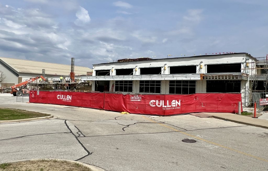 exterior of incomplete cafeteria. Openings where windows will go are visible, as is the exterior fire suppression covering. April 28, 2025.