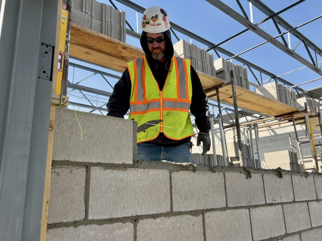 construction worker stacking concrete bricks. April 4, 2025