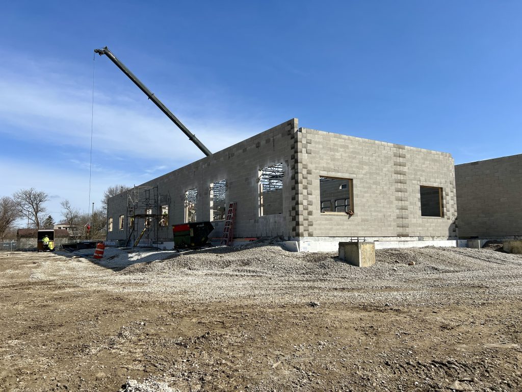exterior of unfinished lannon addition. no roof. no windows. exposed concrete bricks. crane visible.