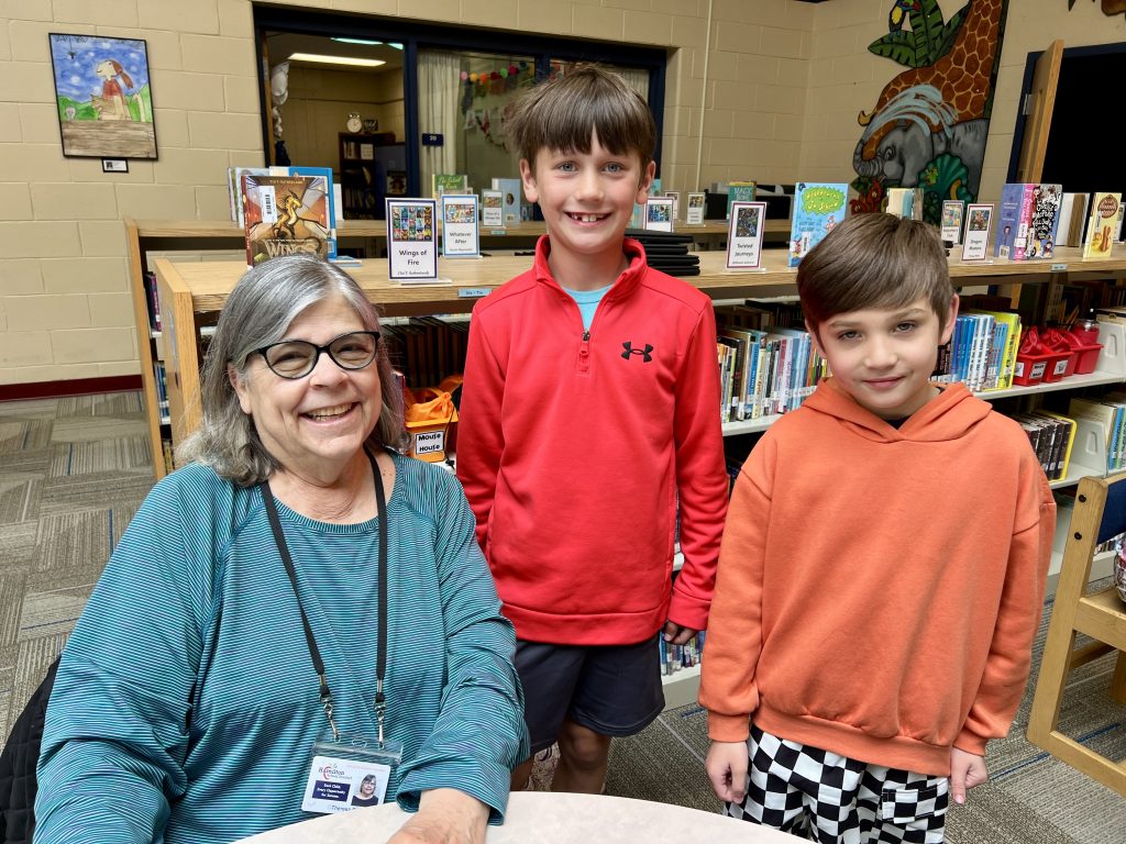 Senior Volunteer with two students smiling.