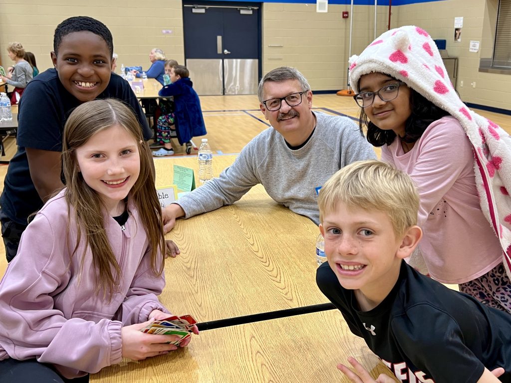 Senior Volunteer with four students smiling.