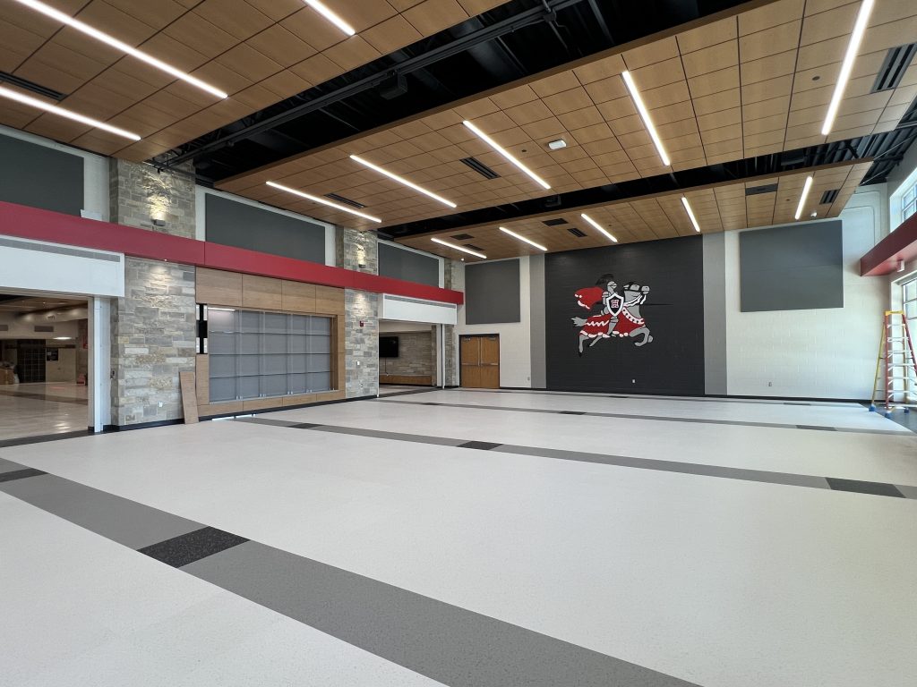 interior of hampton high school cafeteria addition. acoustic ceiling and charger logo on wall.
