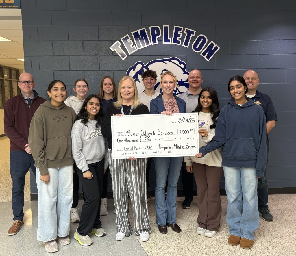 A check is presented to the director of the Sussex Outreach Services surrounded by members of the middle school student council.