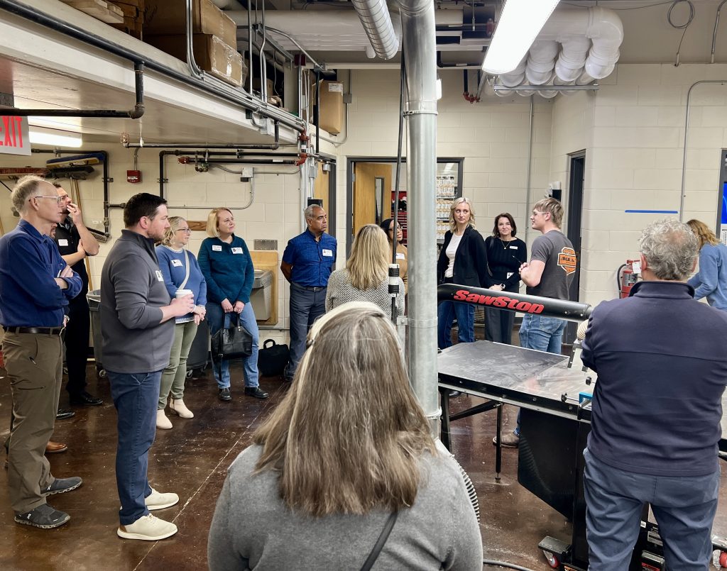 A high school student speaks to Chamber of Commerce members visiting the woods workshop during a tour.